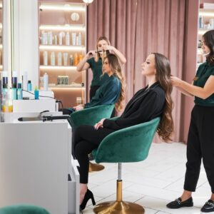 Hairdresser curling woman hair in beauty salon.
