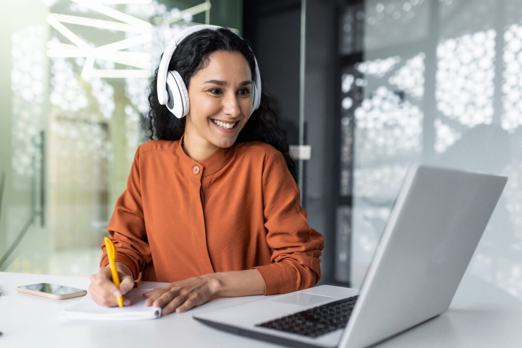 Latin american business woman with curly hair and headphones watching online training course at